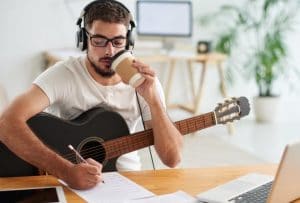 Songwriter with guitar and laptop